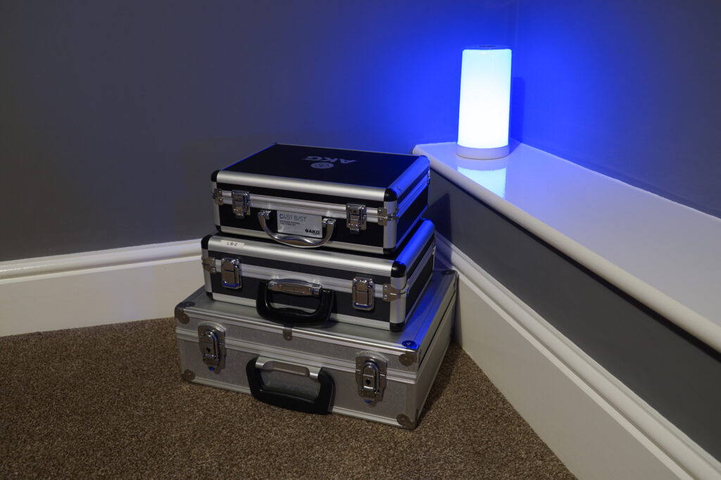 Photo of three microphone boxes with a blue mood light in the corner of the room. The top box is labelled AKG C451B / ST.